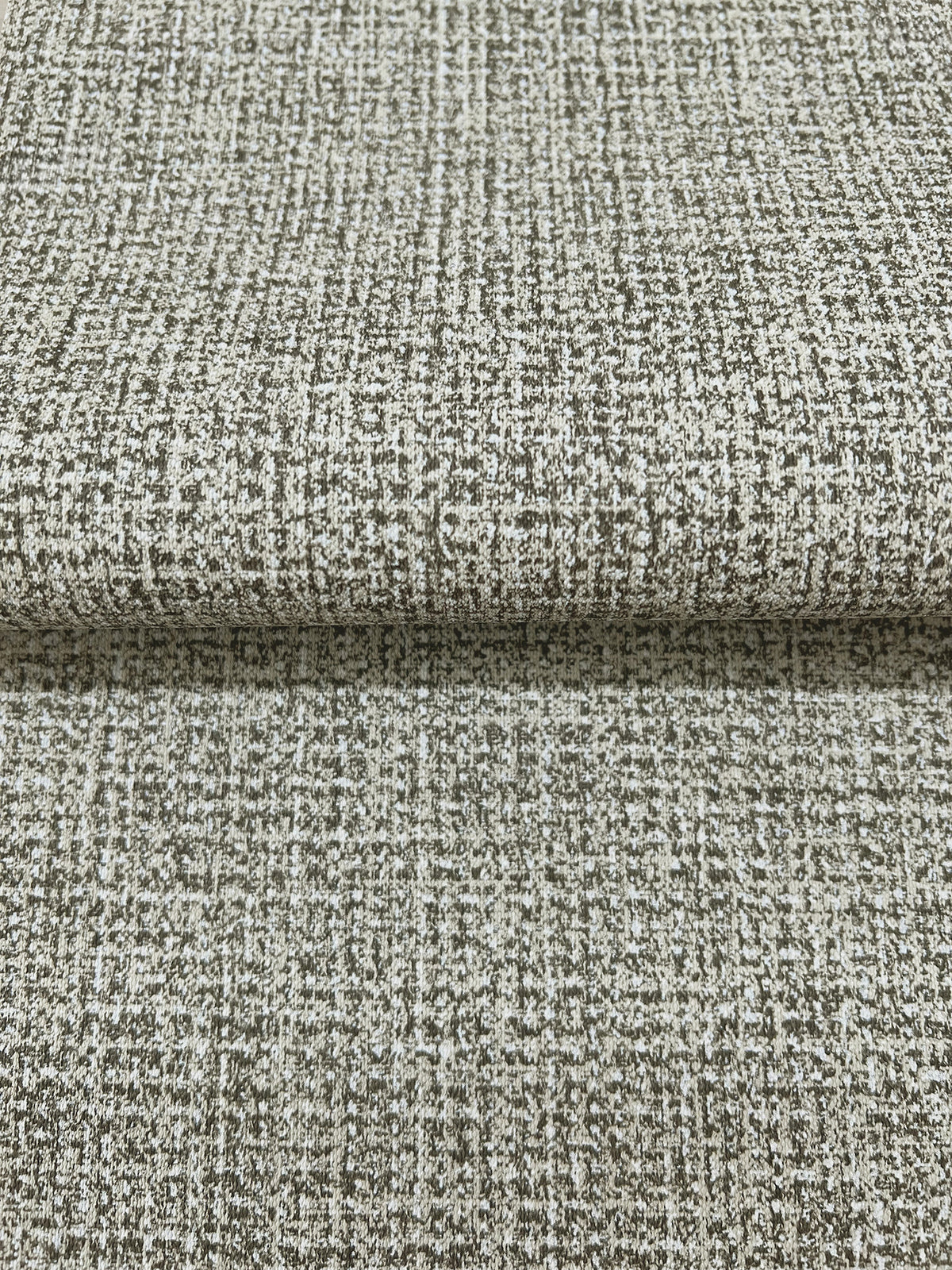Folded sheet of Magnolia Home Brindled Wallpaper featuring a mottled, grid-like pattern in shades of brown and off-white.