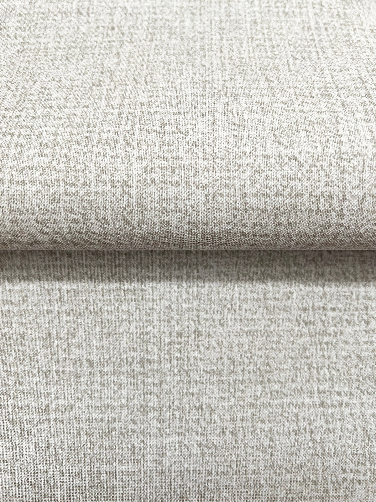 Close-up of a roll of Magnolia Home Brindled Wallpaper in tan with a mottled, textured pattern.