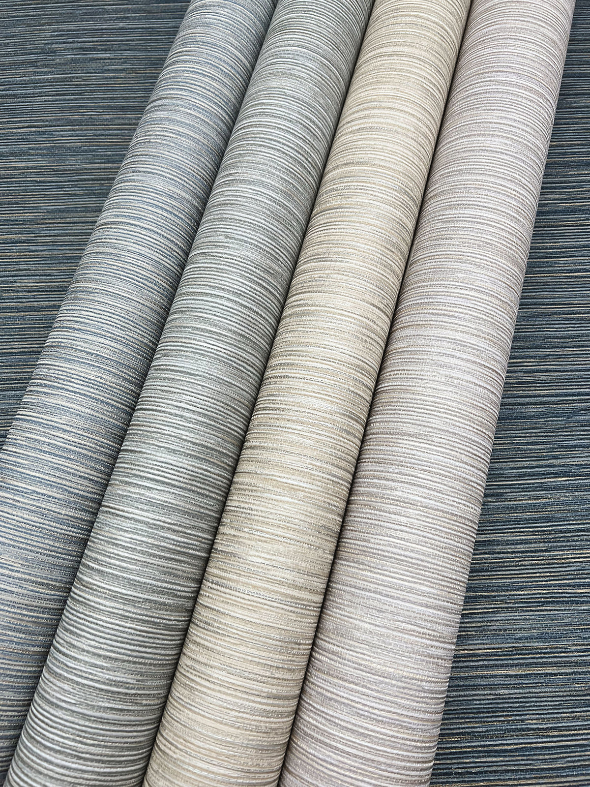 Four rolls of Grass Roots Wallpaper in varying shades of gray, beige, and cream, displaying a horizontal ribbed pattern.