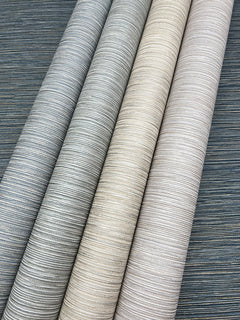 Four rolls of Grass Roots Wallpaper in varying shades of gray, beige, and cream, displaying a horizontal ribbed pattern.