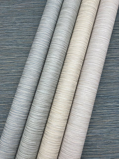 Four rolls of Grass Roots Wallpaper featuring textured, horizontally-striped patterns in shades of dark gray, light gray, beige, and cream.