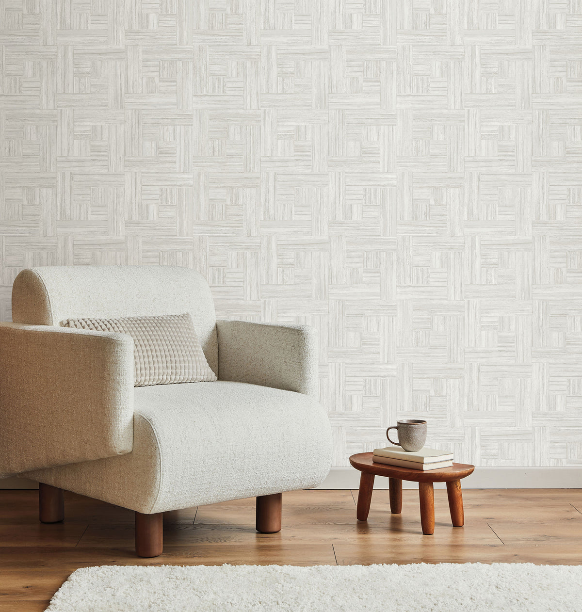 Light-colored Tesselle Wallpaper by York Wallcoverings featuring a repeating geometric pattern of textured squares, shown behind an armchair and a small side table.
