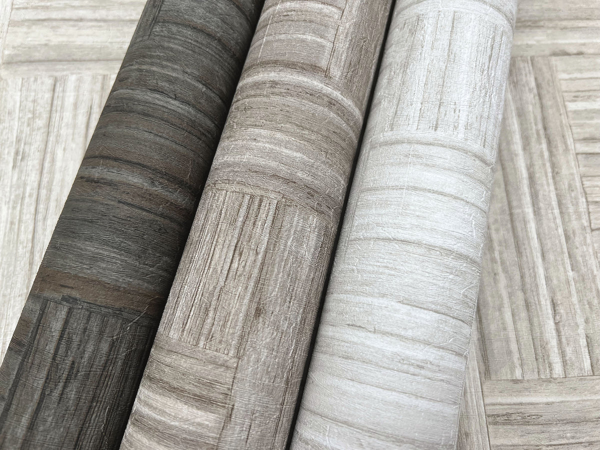 Tesselle Wallpaper in dark gray, brown, and light gray, each featuring a textured wood-grain and geometric block pattern.
