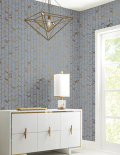 Candice Olson Perfect Petals Wallpaper by York Wallcoverings featuring a repeating vertical pattern of light blue petals outlined in metallic gold, installed on a wall behind a white sideboard and lamp.