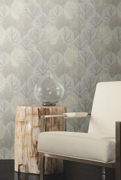 Candice Olson Leaf Concerto Wallpaper featuring a repeating pattern of pale, overlapping leaves behind a wooden side table and a modern armchair.