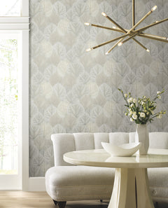 Candice Olson Leaf Concerto Wallpaper featuring a repeating pattern of overlapping, light-colored leaves on a wall behind a curved sofa and dining table.