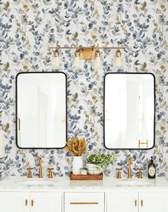 Bathroom vanity with two mirrors and gold faucets set against a wall covered in Candice Olson Joyful Eucalyptus Wallpaper.