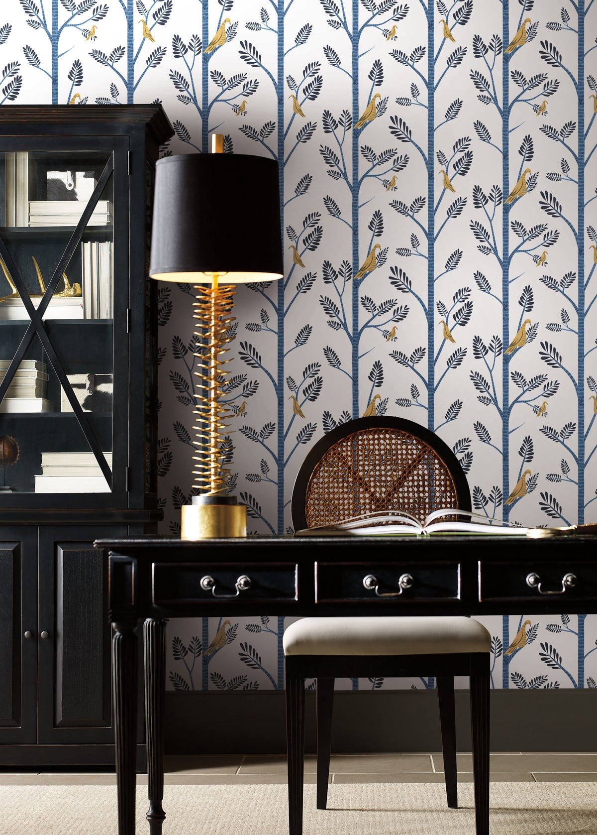Blue Aviary Branch peel and stick wallpaper in a home office with a dark desk and lamp.