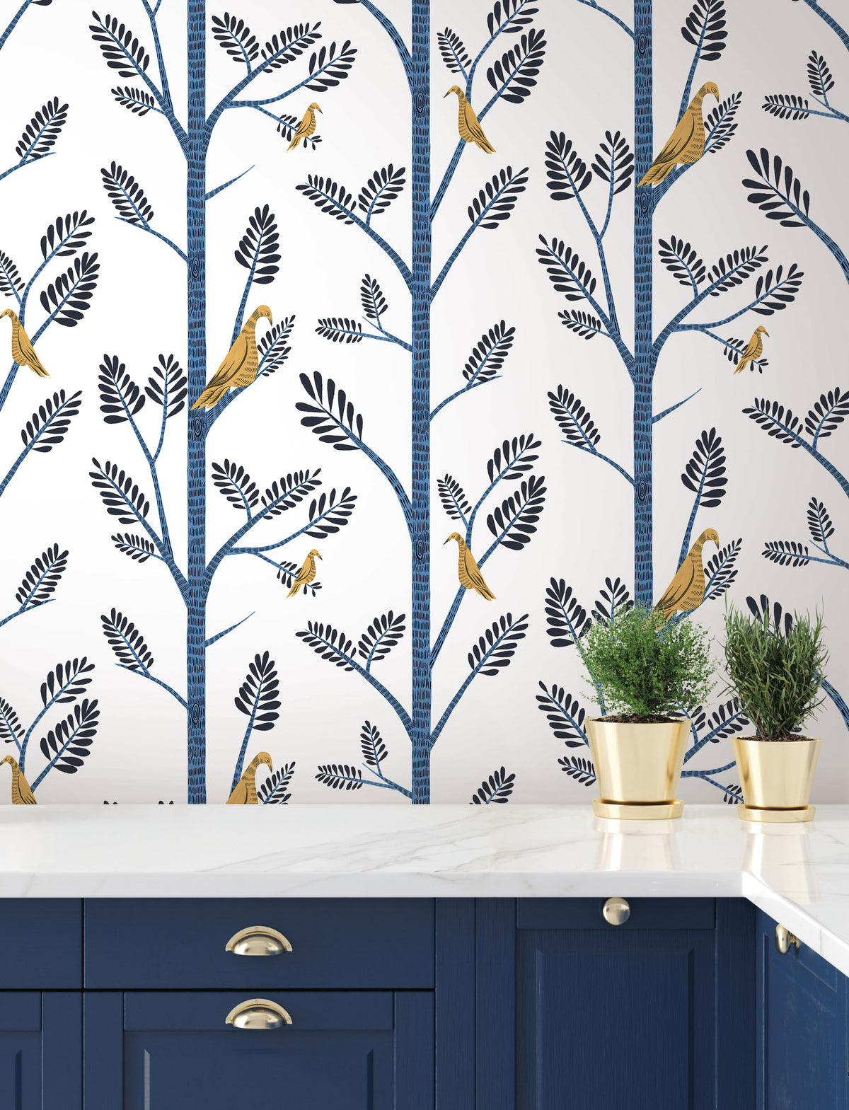 Aviary Branch blue peel and stick wallpaper above a white marble countertop and blue kitchen cabinets.