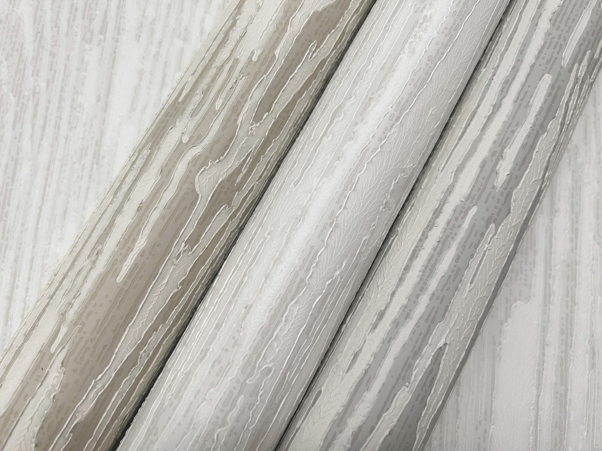 Three rolls of Ronald Redding Heartwood Wallpaper featuring a neutral-toned, abstract wood grain pattern.