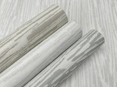 Three rolls of Ronald Redding Heartwood Wallpaper in shades of gray and white with a wood grain pattern.