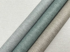 Three diagonal rolls of Ronald Redding Cantilever Wallpaper featuring a textured, linear pattern in shades of grey, muted teal, and bronze, set against a light grey background of the same pattern.