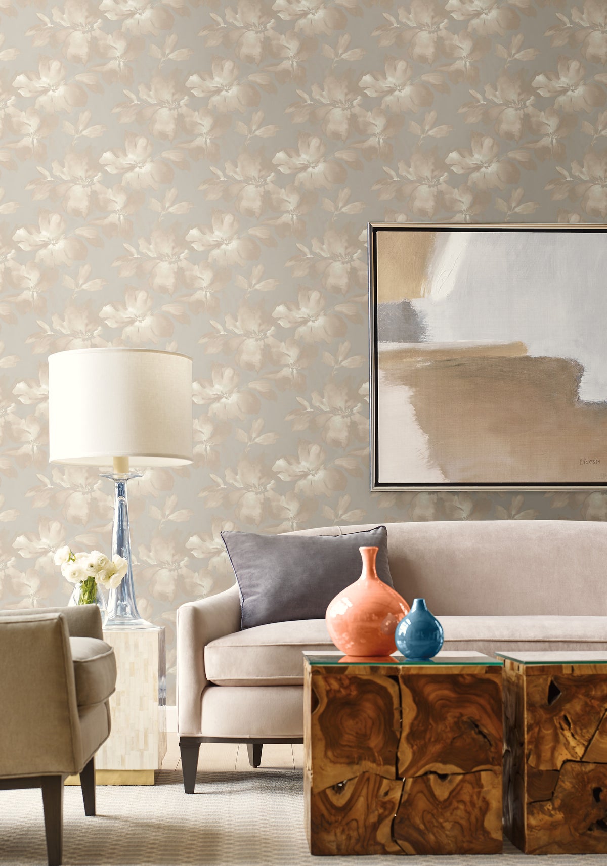Midnight Blooms Wallpaper featuring a light gray pattern of muted beige flowers installed behind a living room sofa with a lamp, abstract art, and wooden side tables.