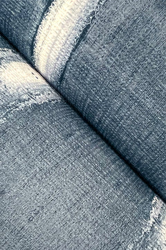 Close-up of York Wallcoverings’ Resound Wallpaper featuring two blue denim-inspired patterns overlapping, with visible weave texture and softly faded curves.