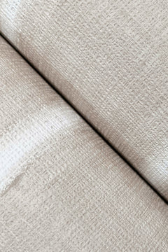 Close-up view of two rolls of York Wallcoverings’ Resound Wallpaper placed side by side, highlighting the subtle woven pattern in textured beige and a visible seam where the rolls meet.