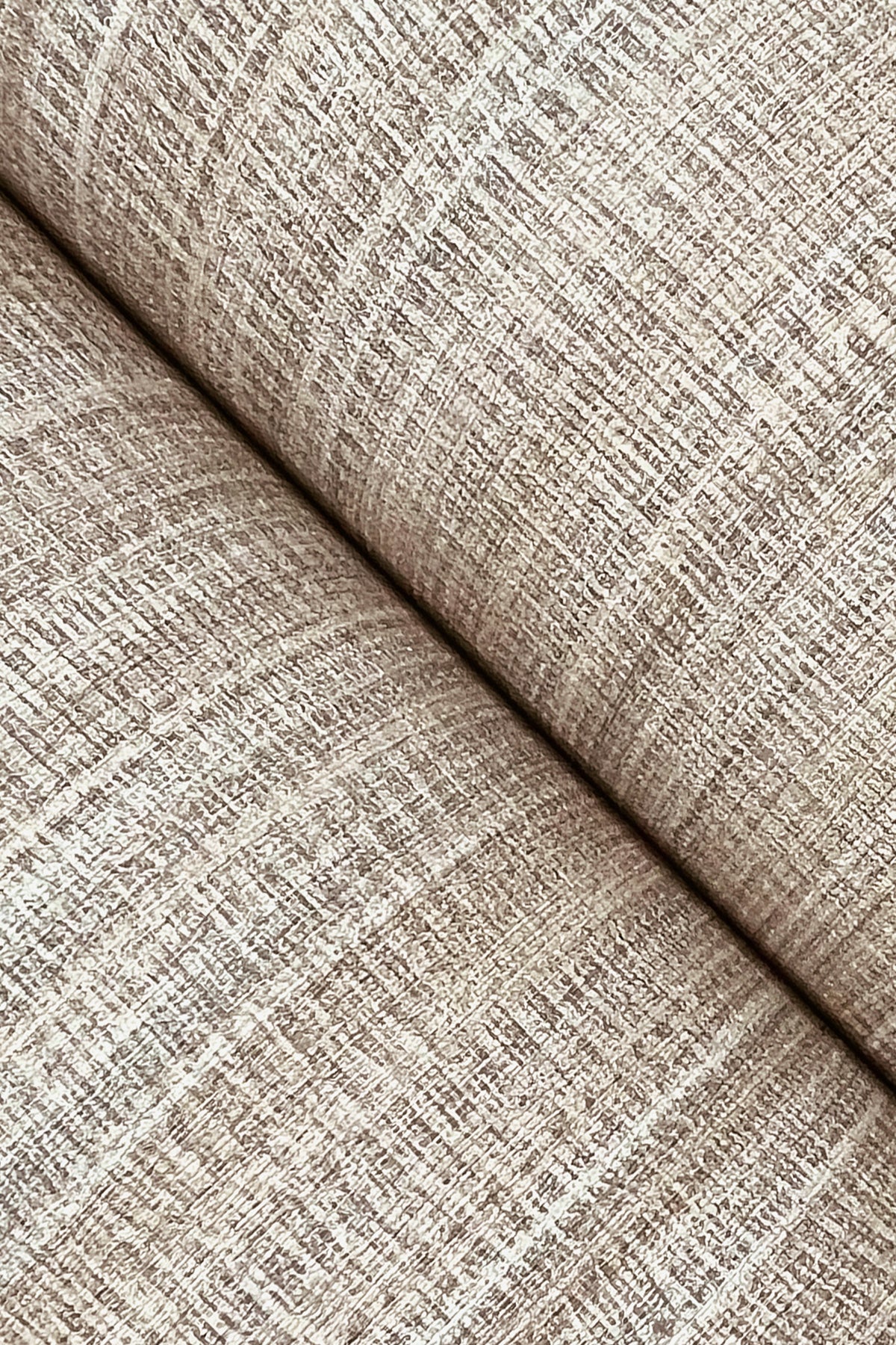 Close-up of York Wallcoverings’ Allineate Wallpaper in beige, highlighting its woven, grid-like texture and diagonal fold, which showcases the fine threads and soft, neutral color.