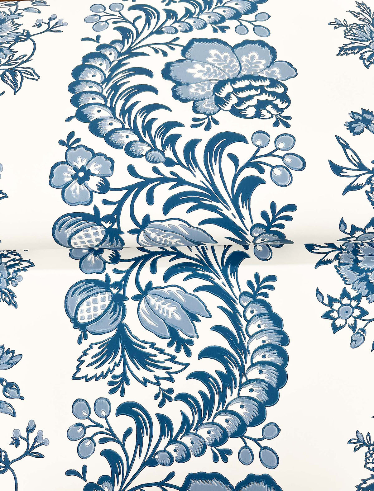 The Beaumont Floral Stripe Wallpaper by York Wallcoverings features a blue and white floral pattern with swirling leaves, flowers, berries, and intricate botanical details set against a light background.