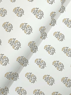 Sylvie Floral Wallpaper by York Wallcoverings features a white background adorned with a repeating pattern of grey leaves and muted yellow flowers; the wallpaper is shown with a visible diagonal crease across the center.