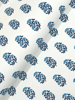 The Sylvie Floral Wallpaper by York Wallcoverings features a white surface adorned with a repeating pattern of dark blue leaves and light blue flowers, uniformly arranged across the material. A diagonal crease is visible in the image.