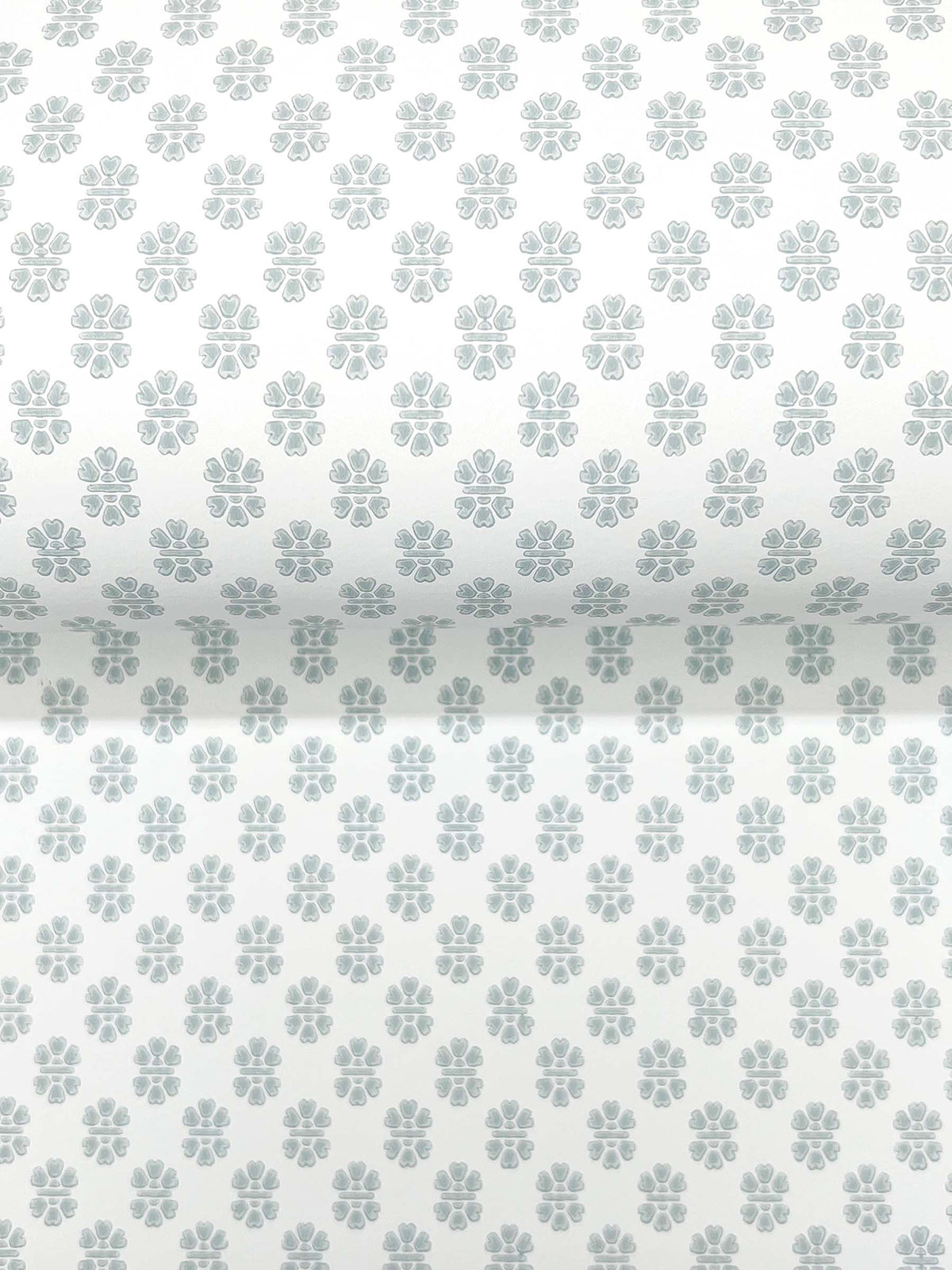 The Brioni Floral Stamp Wallpaper by York Wallcoverings features a roll of white wallpaper adorned with a repeating pattern of small, light gray, four-petal floral shapes.