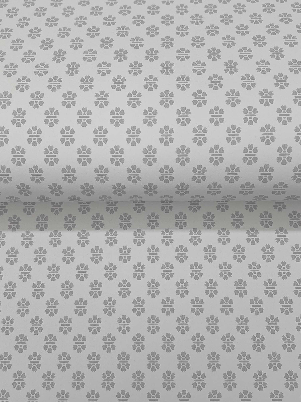 Brioni Floral Stamp Wallpaper by York Wallcoverings features a repeating pattern of small, evenly spaced paw prints in gray. The design extends seamlessly across both vertical and slightly curved horizontal surfaces for a continuous effect.