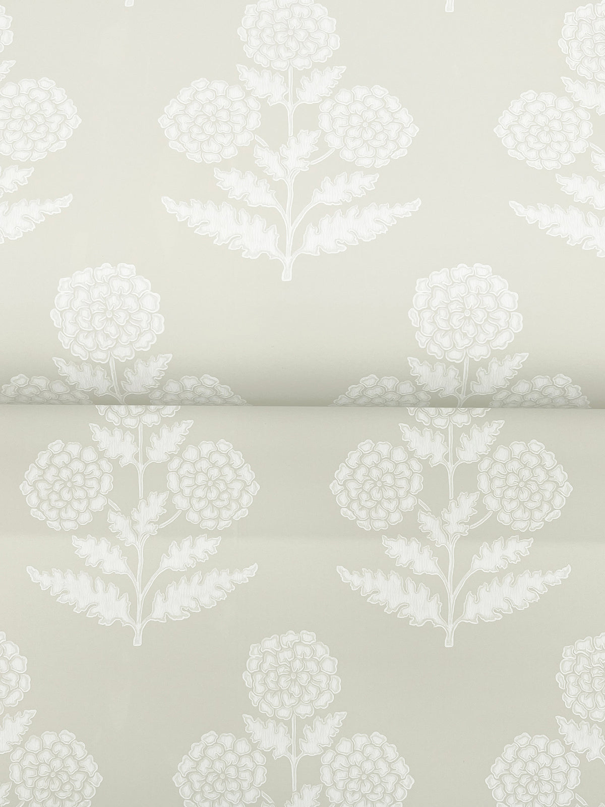 Souci Marigolds Wallpaper by York Wallcoverings features a light gray background adorned with repeating white floral motifs of stylized flowers and leaves arranged in a vertical, symmetrical pattern. The delicate design creates an elegant and understated botanical look.