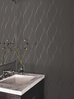 A modern bathroom featuring the Wavy Stripe Wallpaper by York Wallcoverings on a gray wall, complemented by a marble sink, a mirror, and a vase with long-stemmed flowers.